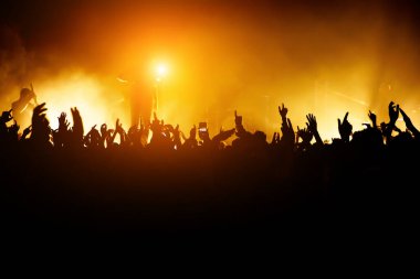 Rock konseri. Lider sahnede. Sahnenin önündeki kalabalığın silueti.