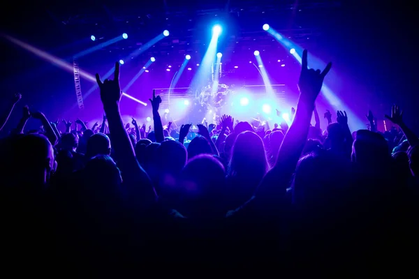 Müzik konserinde elini kaldırmış bir adamın silueti..