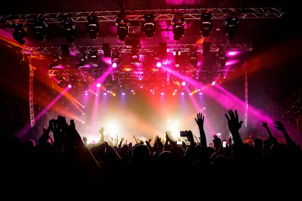 Raised hands in honor of a musical show on stage, People in the hall