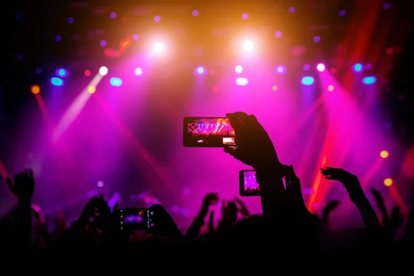 コンサートで手にするスマートフォンステージからの赤い光 — ストック写真
