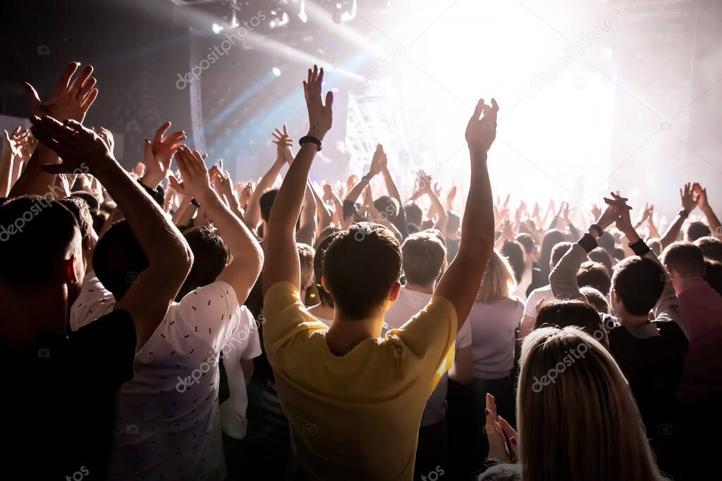 Raised hands in honor of a musical show on stage, People in the hall