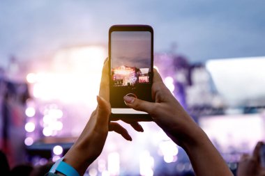 Bir kız telefonda sokak konserinin fotoğraflarını çekiyor.