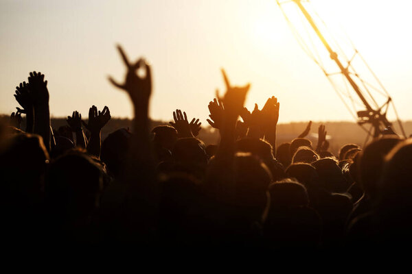 People celebrating on an summer open air. Shillouettes of raised hands