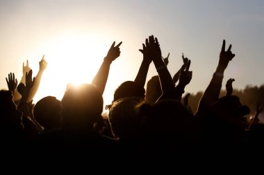 İnsanlar açık havada yazı kutluyorlar. Kaldırılmış ellerin haykırışları