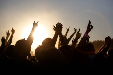 İnsanlar açık havada yazı kutluyorlar. Kaldırılmış ellerin haykırışları