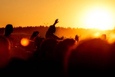 Elleri havada bir adam açık hava rock festivalinde tezahürat yapıyor.