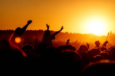 Elleri havada bir adam açık hava rock festivalinde tezahürat yapıyor.