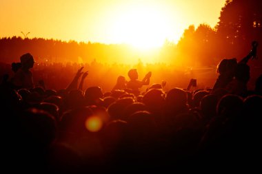 Yaz partisinde kalabalık dans ediyor. Alçak güneş turuncu ışığı. Gün batımı