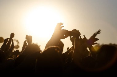 Yaz müzik festivalinde bir sürü el var. Akıllı telefon kullanıyordu. Siluetler