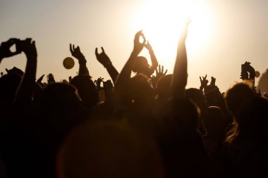 Kalabalık yaz müzik festivalinin, gün batımının, siyah siluetlerin, ortadaki kızın keyfini çıkarıyor.