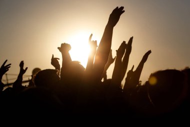 İnsanlar açık havada yazı kutluyorlar. Kaldırılmış ellerin haykırışları