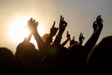 İnsanlar açık havada yazı kutluyorlar. Kaldırılmış ellerin haykırışları