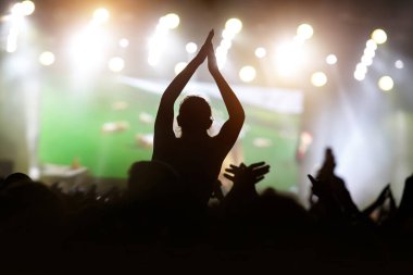 Müzik festivali sahnesine karşı elleri havada bir adam..