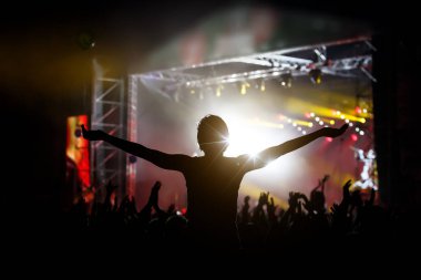 Kız ellerini kaldırıyor ve harika bir konserin tadını çıkarıyor. Siyah siluet