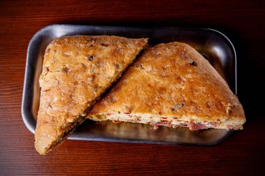 Tahta bir masanın üzerinde üçgen şeklinde yarım bir sandviç.