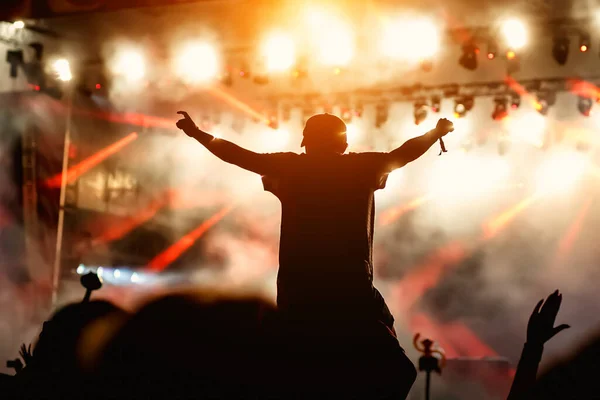 Man with raised hands opposite stage light. Night club party