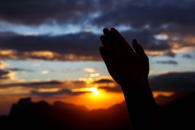 Günbatımı arka planında dua eden eller. Siyah siluet