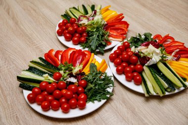 Yuvarlak beyaz tabaklarda taze sebzeler.