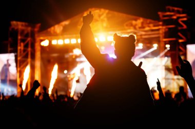 Müzik konserinde elini kaldırmış bir kız silueti..