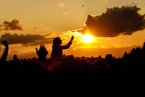 The young woman takes pictures of the festival on her smartphone. Black silhouette over sunset