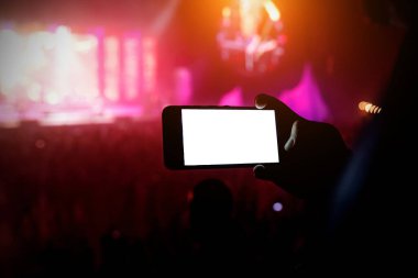 Konserde akıllı telefonlu bir el silueti. Boş beyaz ekran