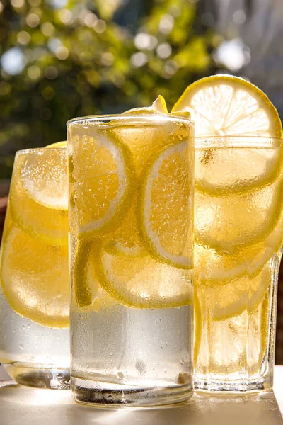 日当たりの良い庭の背景にレモン水の3つのガラス クローズアップビュー — ストック写真