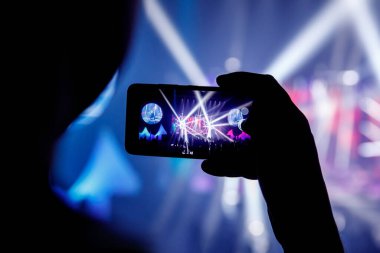 Konserde akıllı telefonlu bir el silueti. Kayıt gösterimi