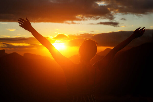 The girl joyfully raised her hands at dawn.