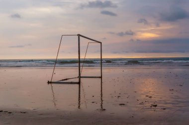 Gün batımında okyanus sahilinde futbol kapısı.