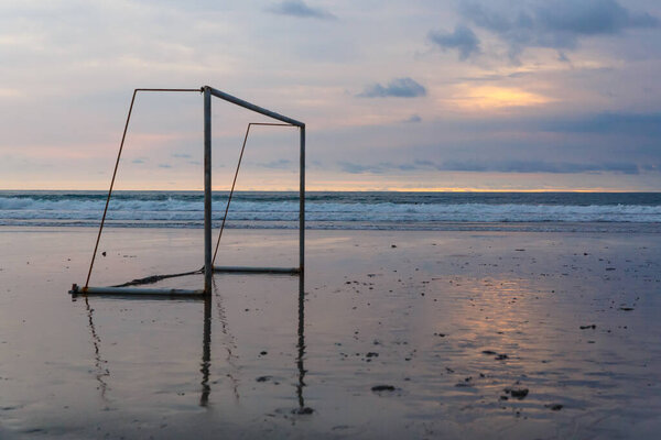 Футбольные ворота на берегу океана на закате