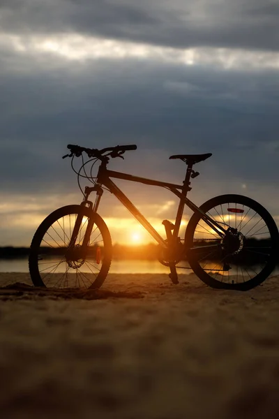 La silueta de la bicicleta deportiva en la playa. Puesta de sol. — Foto de Stock