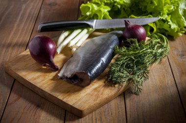 Kırmızı soğan, marul, chives ve dereotu ahşap kesme tahtası ile ringa balığı.