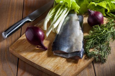 Kırmızı soğan, frenk soğanı, marul ve dereotu ile ahşap kesme tahtası üzerinde ringa balığı. Close.