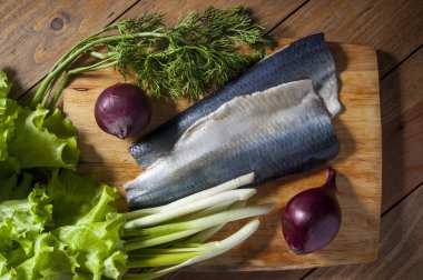 Kırmızı soğan, frenk soğanı, marul ve dereotu ahşap kesme tahtası ile ringa balığı. Yukarıdan görüntülemek.