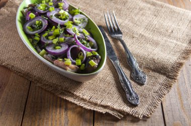 Ringa balığı, kırmızı soğan, dereotu ve Frenk soğanı altında dilim fileto. Bıçak ve çatal çuval bezi üzerinde yakın. 