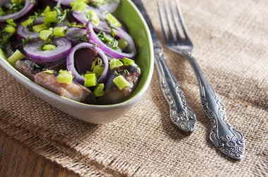 Dilimleri altında kırmızı soğan ve bıçak ve çatal çuval bezi üzerinde ringa balığı filetosu. Yakın çekim.