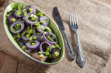 Ringa balığı, kırmızı soğan, dereotu ve Frenk soğanı altında dilim fileto. Bıçak ve çatal üzerinde çul. 