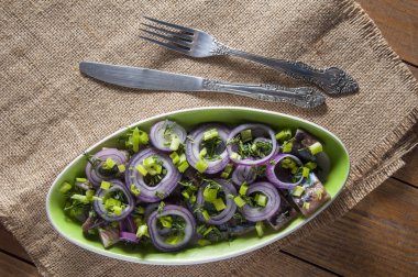 Ringa balığı, kırmızı soğan, dereotu ve Frenk soğanı altında dilim fileto. Bıçak ve çatal çuval bezi üzerinde yakın. Yukarıdan görüntülemek.