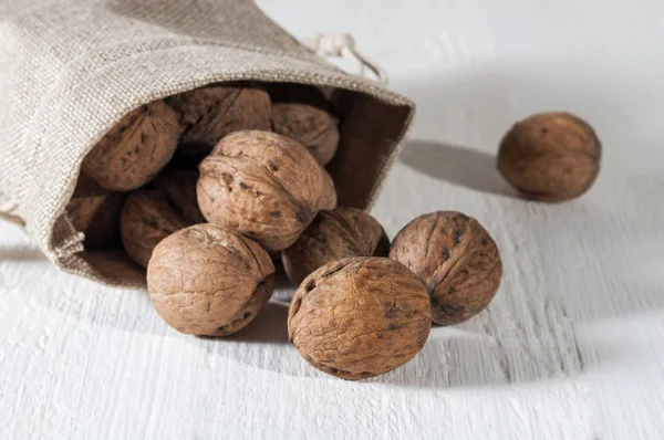 Walnüsse Einem Beutel Teilweise Ausgerollt Auf Einem Weißen Holztisch — Stockfoto