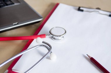 Masadaki kırmızı panoda kırmızı steteskop ve kırmızı kalem. Ne?