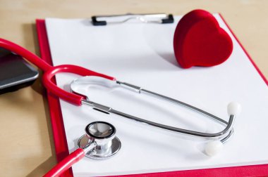 Kırmızı bir panoda kırmızı stetoskop ve kalp. Dizüstü bilgisayarın yanında. Medic cihazı.