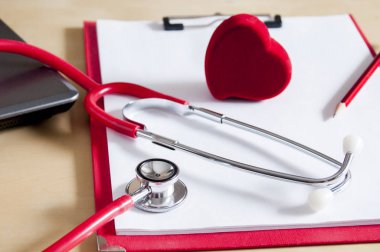 Kırmızı steteskop, kırmızı kalem ve kalp kırmızı bir panoda. Yaklaştın!