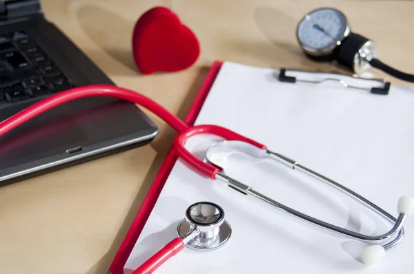빨간색 청진기, 빨간색 클립 보드에 토노미터. 노트북과 심장 근처. 의료 기기. — 스톡 사진