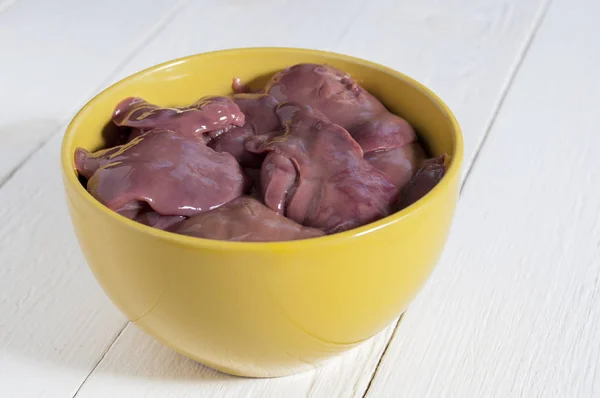 Hígados de pollo crudos en un tazón amarillo sobre una mesa de madera blanca. Clo. —  Fotos de Stock