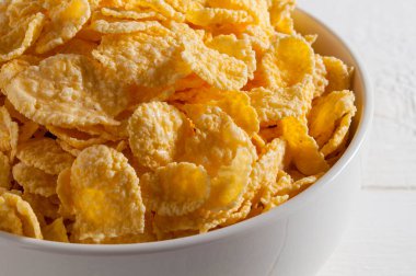 Çerçevenin sol tarafındaki beyaz ahşap bir masada beyaz mısır gevreği kasesi. - Yakın çekim..