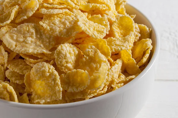 Çerçevenin sol tarafındaki beyaz ahşap bir masada beyaz mısır gevreği kasesi. - Yakın çekim..