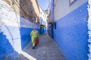 : Chefchaouen, Morocco Medine'de yürüyen kadın. Geleneksel Fas mimari detaylar ve boyalı evleri. çiçekler ve kemer ile parlak mavi duvarları 