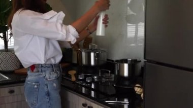 Asyalı kadın ev kadınları yemek pişirip mutfaktaki çorba kabına tuz ekliyorlar..