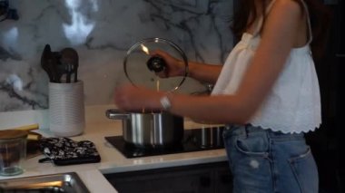  Asyalı kadın ev kadınları yemek pişirip mutfaktaki çorba kabına yumurta koyuyorlar.