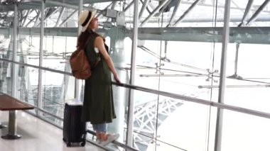 Backpacker gezginler Asyalı kadınlar havaalanında uçak bağlama sırasında ağrı ve germek hissetmek için Transit bekliyor şapka giyiyor. Tatil ve seyahat konsepti
